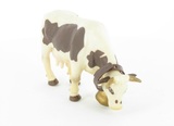 Vache brun et blanc broûtant avec cloche